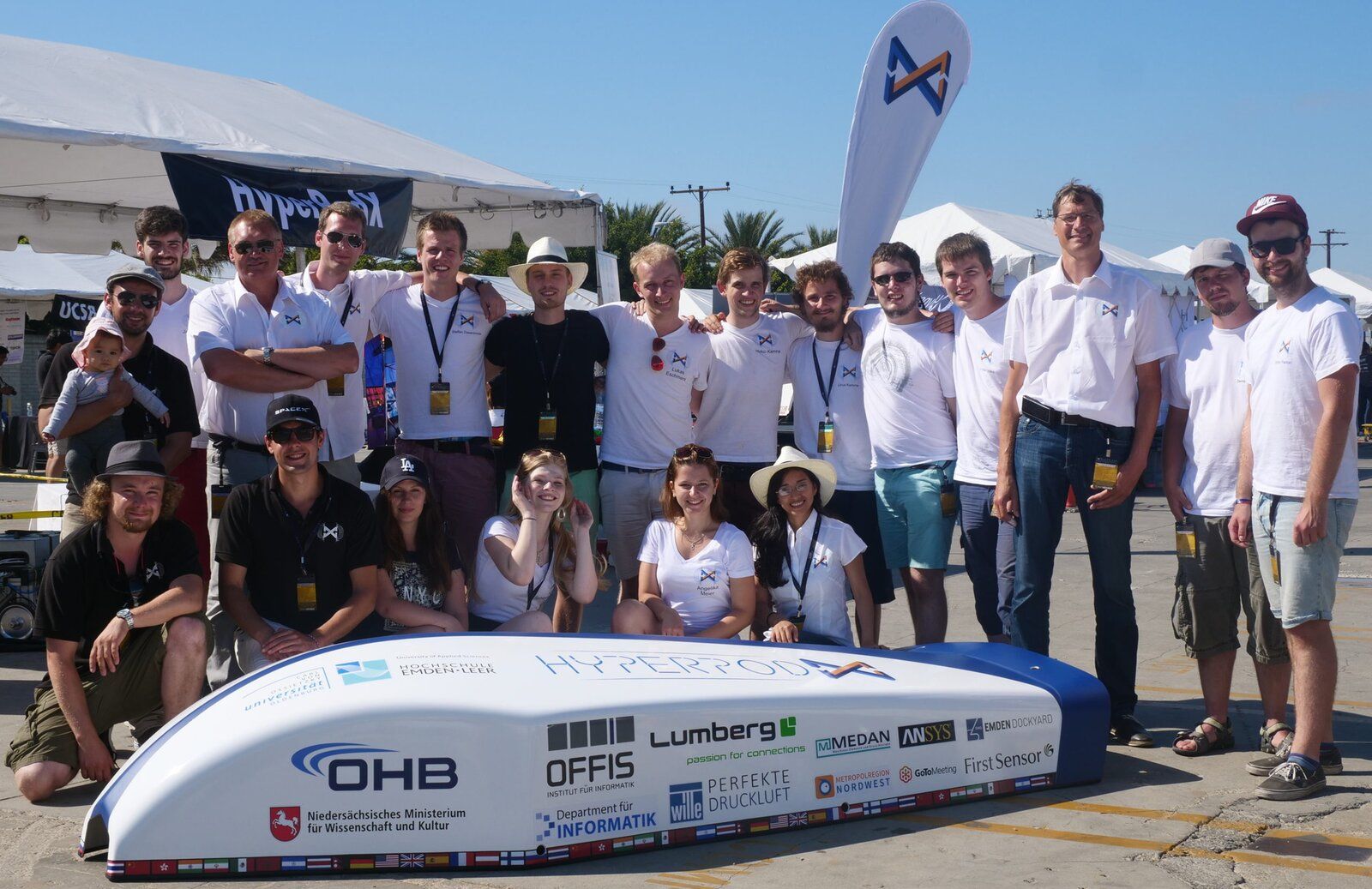 The HyperPodX team around the finished white-and-blue pod shell at the SpaceX competition in Hawthorne, California